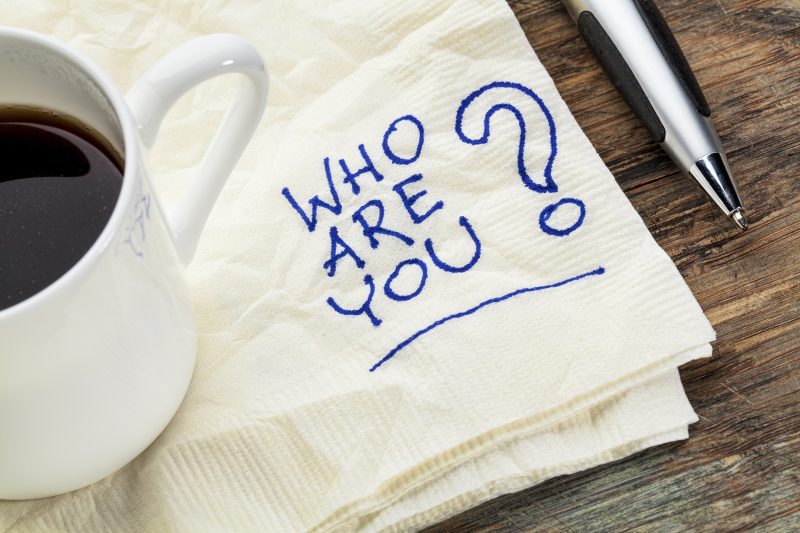 who are you question written on a napkin with a cup of coffee
