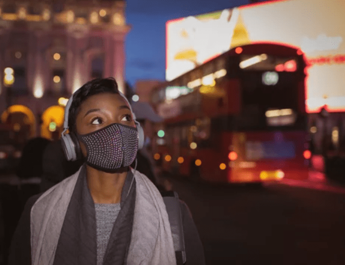 Person with a mask on to protect from viruses standing in front of a bus in a city