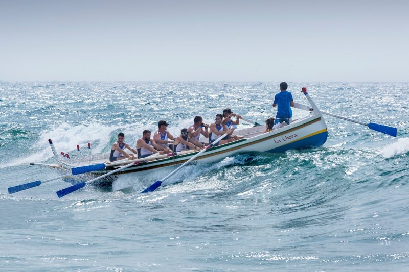 Coxswain on a boat at sea motivating the rowers