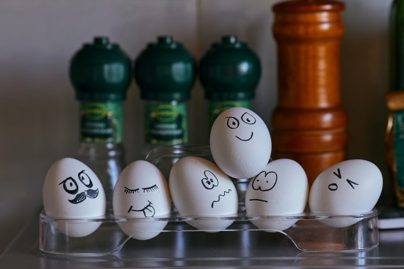 Eggs in a kitchen on egg cups with different expressions drawn on the shells