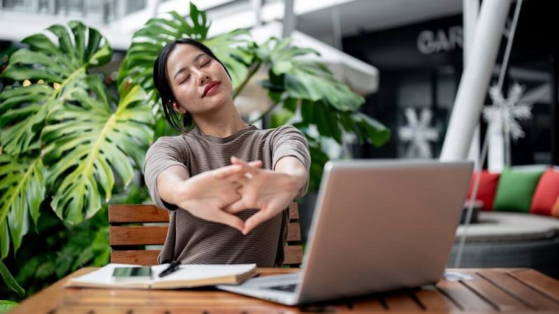 Calm woman stretching in front of her laptop