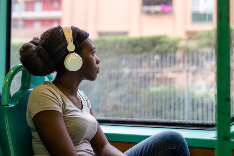 Woman on a bus looking out of the window with headphones on.